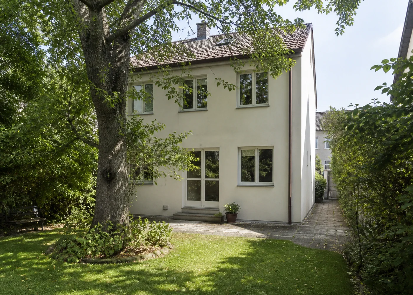 Gartenseite eines Wohnhauses mit Seitenweg und altem Baum